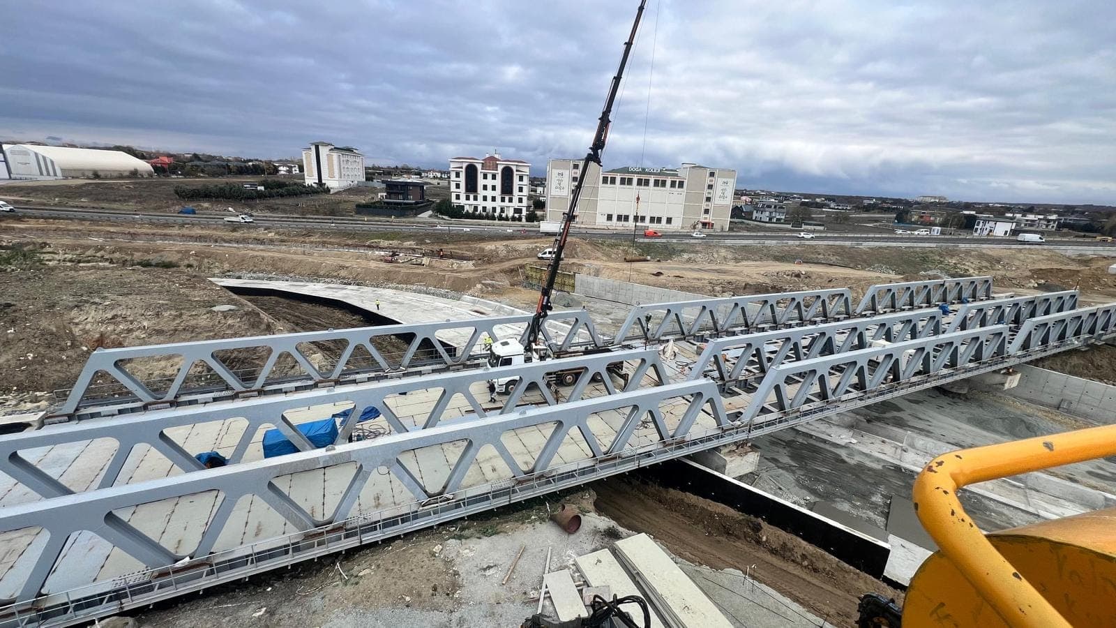 Mobil vincin halatlarıyla havada tutulan kafes kiriş; üst ve alt başlıklar arasında dikmeli diyagonal örgü açıkça görünüyor
