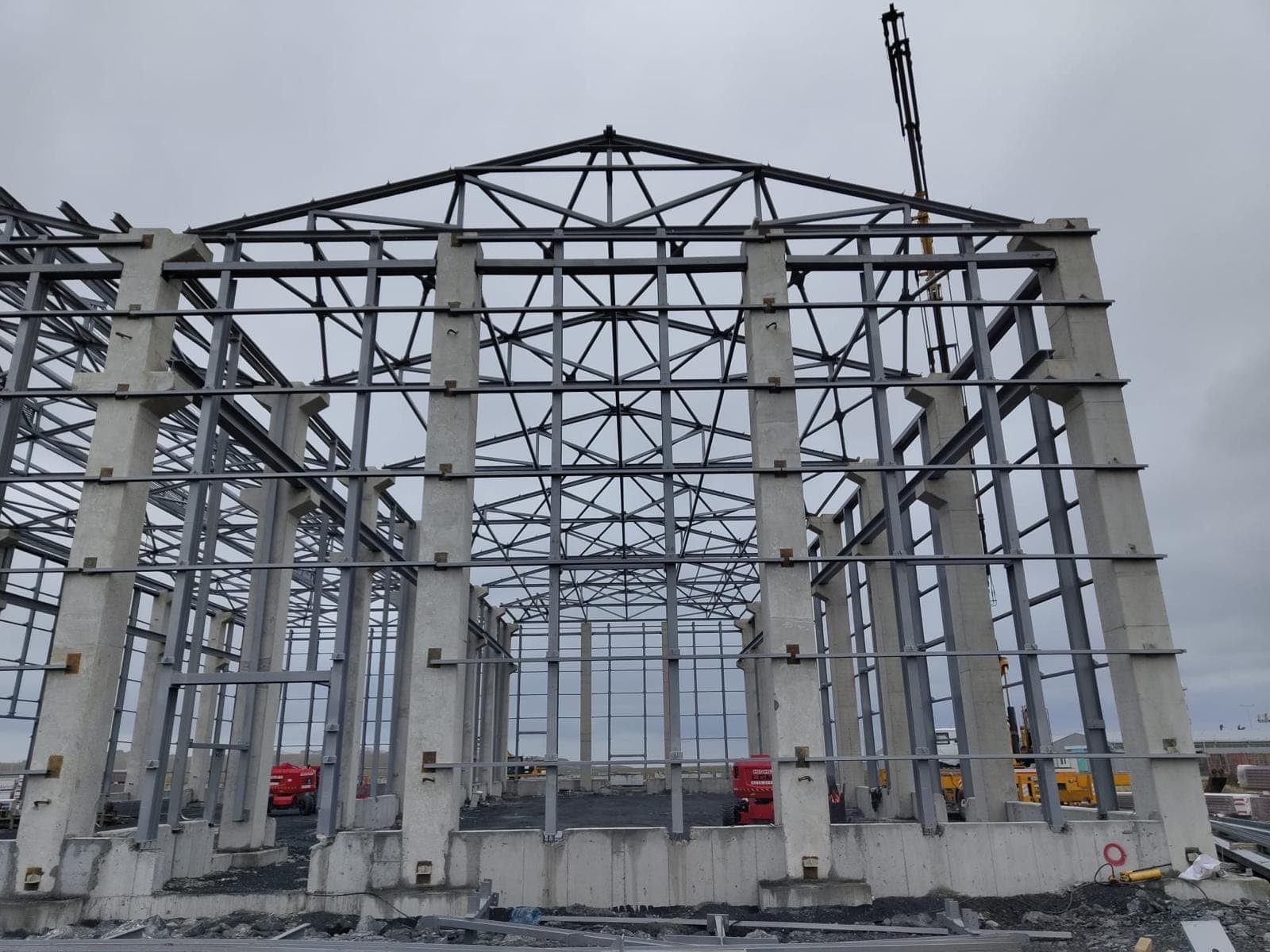 Hangar yapısının alın cephesi; prefabrik beton kolonlar üzerine oturan kafes makaslı beşik çatı, alın düzleminde çapraz bağlantılar, arkada vinç bomu