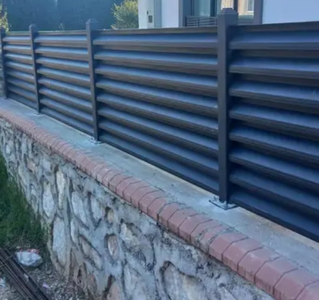 Taş duvar üzerine monte edilmiş antrasit renkli panjur korkuluklu bahçe çiti